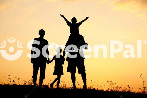 Happy Family On Meadow At Summer Sunset
